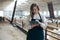 Young Caucasian Female Farm Owner with Tablet in large Livestock Stall with white Dairy Goats