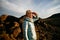 Young caucasian female hiker gazing while standing on top of mountain at sunset.