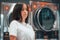 Young Caucasian female standing in front of laundry machines