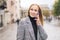 A young Caucasian girl in a coat is talking on a mobile phone and attentively listens to information