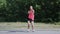 Young caucasian girl in pink shirt with headphones dancing in park. Attractive woman doing funny and ridiculous moves. Girl smilin