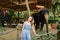 Young caucasian girl standing near tamed and tied elephants.