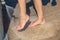 Young caucasian girls rinsing sand off their feet with a jet of water at foot washing station with a faucet