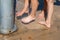 Young caucasian girls rinsing sand off their feet with a jet of water at foot washing station with a faucet