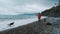 Young Caucasian guy walks along pebbly seashore with Australian and German Shepherd dogs. Male Owner and pets on