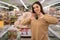 Young Caucasian lady in a supermarket buys an avocado. A woman buys groceries and basic goods at a local organic store