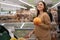 Young caucasian lady in a supermarket buys a pomelo. A woman buys groceries and basic goods at a local organic store