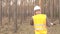 Young caucasian male inspector in a signal vest talking on the phone against the backdrop of the forest industry, copy