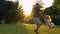 Young Caucasian male parent playing with happy little daughter on nature outdoor. Father spinning girl in park. Kid