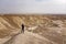 Young caucasian man in baseball cap staying alone in desert and looking ahead to the horizon. Young traveller discovering lifeless