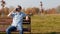 A young caucasian man in black glasses sits in a park on a bench and drinks coffee, slow-mo, copy space