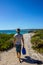 Young caucasian man with a blue bag walking down a pathway to Hamelin Beach. This Beach is famous for his stingrays, Hamelin Beach