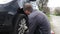 Young Caucasian Man changing tires on the car on the side of the road