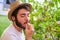 Young caucasian man eat a cherry tomato from a tomatoe plant.