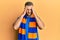 Young caucasian man football hooligan cheering game with hand on head, headache because stress