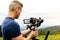 Young caucasian man handling a camera on top of a gimbal while working on recording a scene