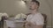 Young Caucasian man holding basin and looking up at leaking ceiling. Handsome guy with bucket having household problem