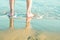 Young Caucasian Man Male Standing Barefooted on Beach Sand by Turquoise Sea. Waves Washing his Feet. Soft Golden Sunlight.