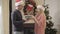 Young Caucasian man in New Year hat giving gift box to pretty woman. Cute girl opening present and making dissatisfied