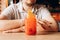 Young caucasian man and Red Strawberry lemonade with ice,  cocktail tube and orange slice in glass with handle on wooden table.