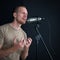 Young caucasian man singing in front of black soundproofing walls. Musicians producing music in professional recording studio