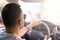 Young Caucasian man sitting in a car rear view holding the steering wheel; watching the translation on a bright sunny day