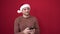 Young caucasian man smiling using smartphone wearing christmas hat over isolated red background