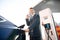 Young Caucasian man stands at the charging station and inserts a plug of the charger for an electric car