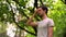 A young caucasian man stands in a park and puts a napkin to his head because of a headache