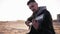 Young caucasian man, stylish bearded standing outdoors on the autumn beach and playing guitar at amazing evening with