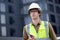 Young caucasian man using radio conversation and inspecting while building and tower all around.