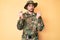 Young caucasian man wearing camouflage army uniform doing money gesture with hands, asking for salary payment, millionaire