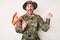 Young caucasian man wearing camouflage army uniform holding spanish flag screaming proud, celebrating victory and success very