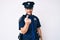 Young caucasian man wearing police uniform beckoning come here gesture with hand inviting welcoming happy and smiling