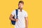 Young caucasian man wearing student backpack and headphones thinking attitude and sober expression looking self confident