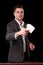 Young caucasian man wearing suit holding two aces in his hand on black background. Gambling concept. Casino