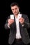 Young caucasian man wearing suit holding two aces in his hands on black background. Gambling concept. Casino