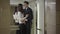 Young Caucasian man and woman hugging and kissing on business center. Elevator door opens and embarrassed couple walking