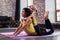 Young Caucasian mother doing yoga cobra pose on floor while her smiling daughter sitting on moms back hugging her in