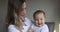 Young caucasian mother and her baby daughter hugging and playing at home in bedroom. Little kid seven months old