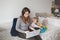 Young Caucasian mother with toddler baby working on laptop from home. Workplace of freelance woman student with kid. Online