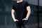 Young caucasian muscular man wearing black tshirt and jeans posing in center of modern city. Blurred background