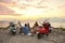 Young caucasian people, motorcycle riders enjoying the view while having picnic on the beach at sunset