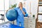 Young caucasian physiotherapist woman holding pilates ball covering mouth with hand, shocked and afraid for mistake