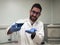 Young caucasian researcher is happily playing with a flask with a blue liquid and dry ice inside