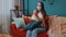 Young Caucasian sick woman wearing medical protection mask sitting in living room looking at camera