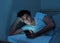 Young caucasian sleepless man bored in bed surfing on the Internet addicted to mobile phone