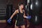 A young Caucasian woman actively trains in the gym and do boxing exercises in boxing gloves in front of a punching bag