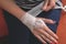 Young caucasian woman is bandaging her wounded palm and wrist indoors. Wraps the hand with a gauze bandage to stop bleeding. Top