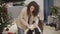 Young Caucasian woman with brunette curly hair combing big Saint Bernard. Happy pet resting with his owner at home. Girl